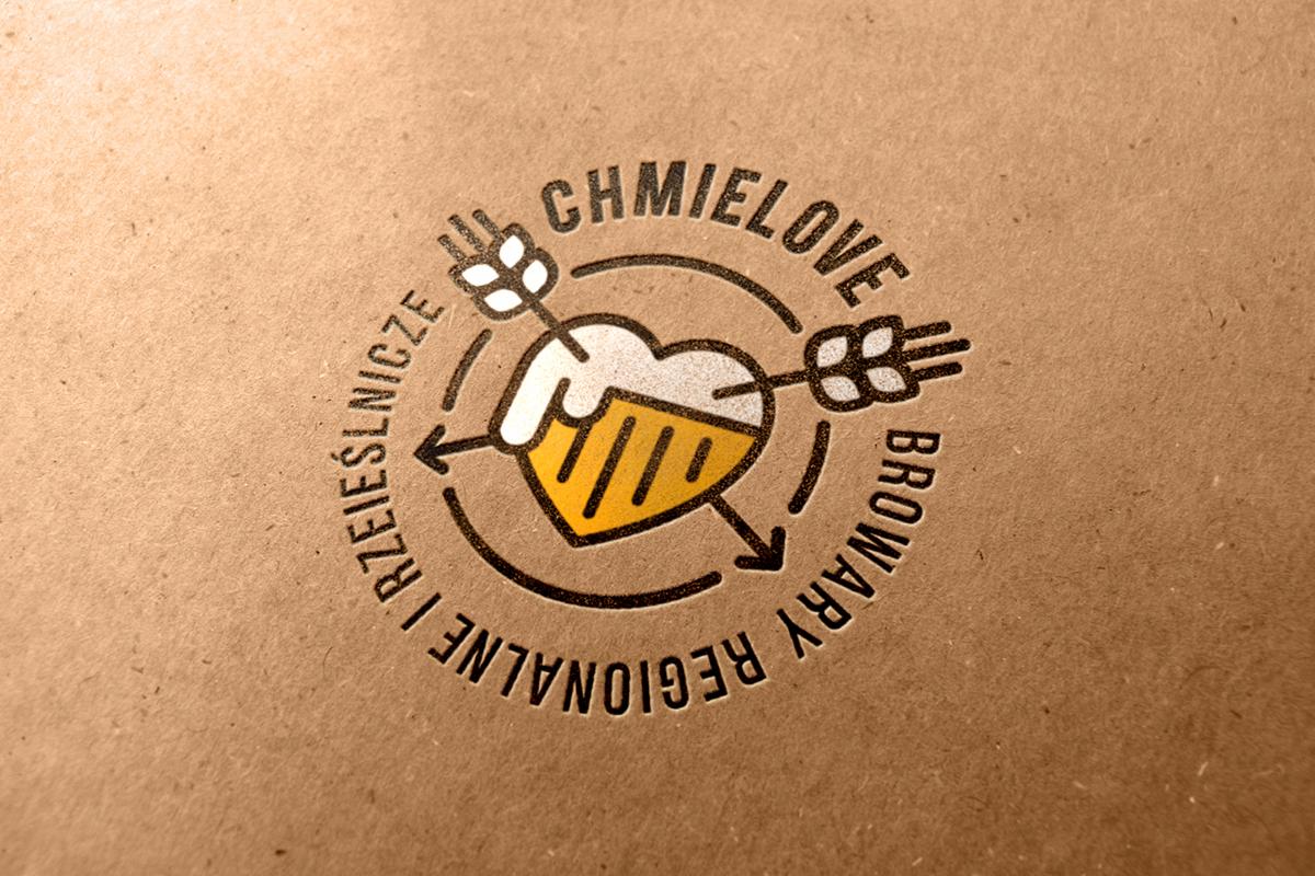 Stylizowane logo browaru 'Chmielove' z motywem serca wypełnionego piwem, przebitego strzałami z chmielu, umieszczone na tekturowym tle.