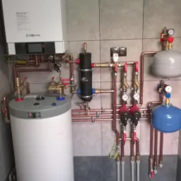 Złożona instalacja centralnego ogrzewania z piecem gazowym Viessmann, zbiornikiem buforowym i filtrem magnetycznym, wykonana w kotłowni w Sieciechowie. Widoczne miedziane rury, manometry i zawory.