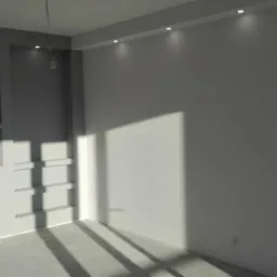 Pomalowane na szaro-biało wnętrze z oświetleniem punktowym w suficie i wnękami w ścianie, z widocznymi promieniami słonecznymi padającymi na podłogę.