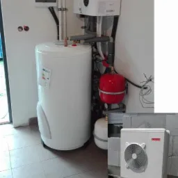 Kompaktowa kotłownia z zasobnikiem ciepłej wody, wiszącym piecem i zewnętrzną jednostką pompy ciepła na betonowych fundamentach