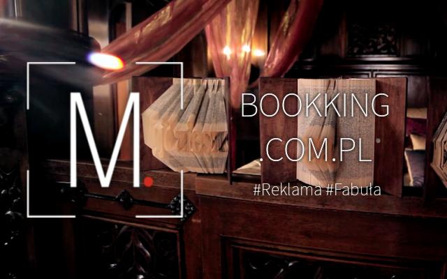 Stylizowana dekoracja wnętrza z książek, z logo firmy BOOKKING.COM.PL i hasztagami #Reklama #Fabula, oświetlona ciepłym światłem.