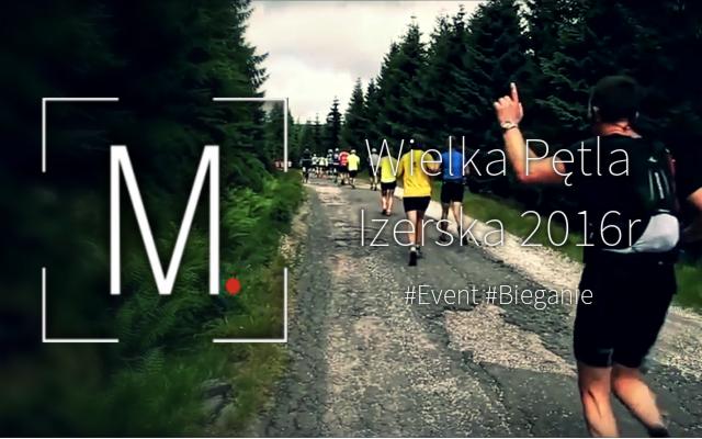 Uczestnicy biegu Wielka Pętla Izerska 2016 na leśnej drodze, widoczny mężczyzna z podniesionym palcem wskazującym, logo imprezy w lewym dolnym rogu.