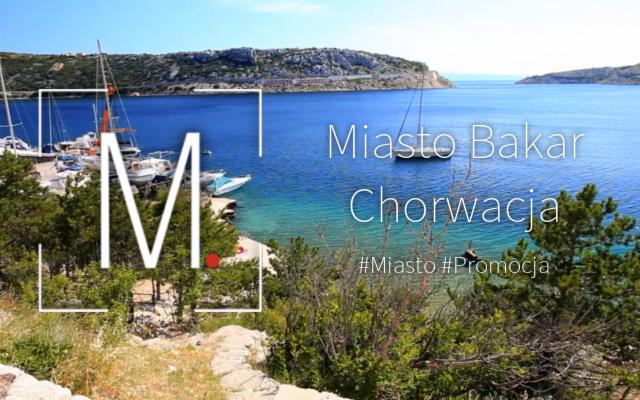Widok na zatokę z łodziami w chorwackim mieście Bakar, z roślinnością na pierwszym planie i napisem 'Miasto Bakar Chorwacja' nałożonym na obraz.