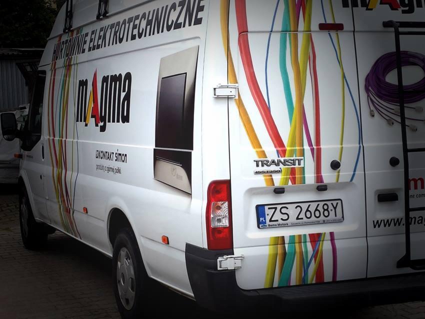 Biały samochód dostawczy z kolorową grafiką przedstawiającą kable i logo firmy 'magma' oferującej hurtowe artykuły elektrotechniczne.