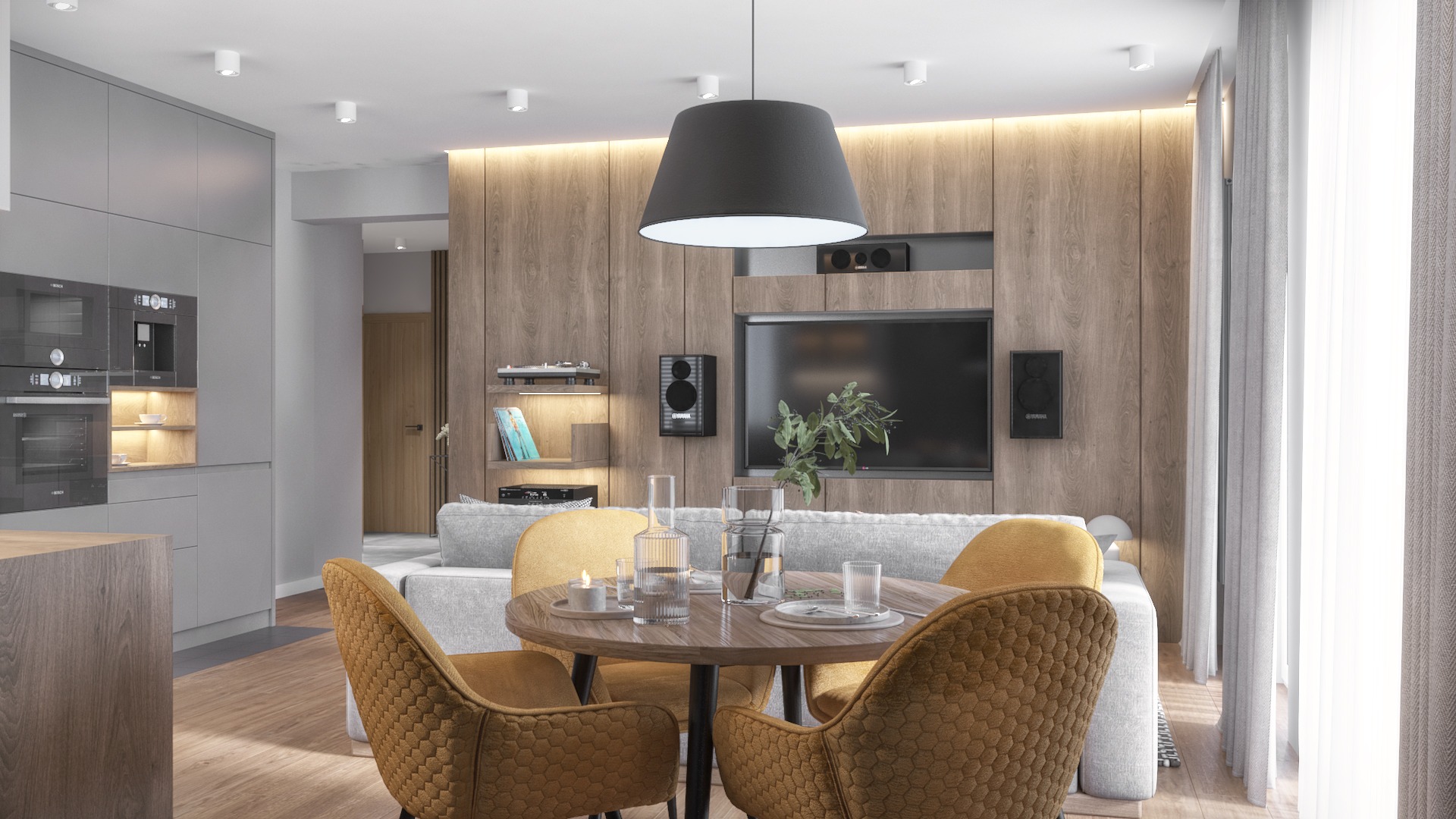 Jasne wnętrze mieszkania z drewnianą ścianą, okrągłym stołem i żółtymi krzesłami w stylu retro, szara sofa i minimalistyczna kuchnia w tle.