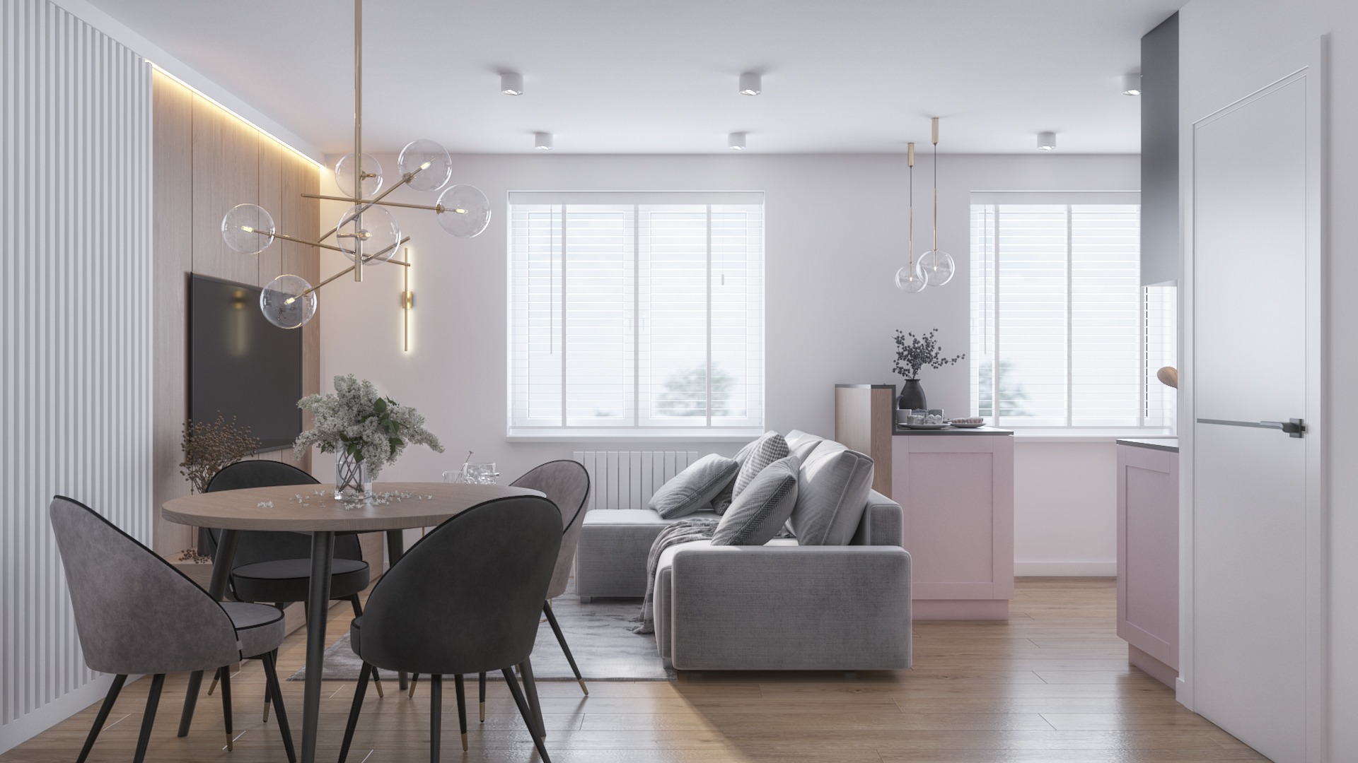 Jasne, nowoczesne wnętrze mieszkania: okrągły stół z szarymi krzesłami, sofa z poduszkami, różowa zabudowa kuchenna, drewniana podłoga i designerska lampa ze szklanymi kulami.