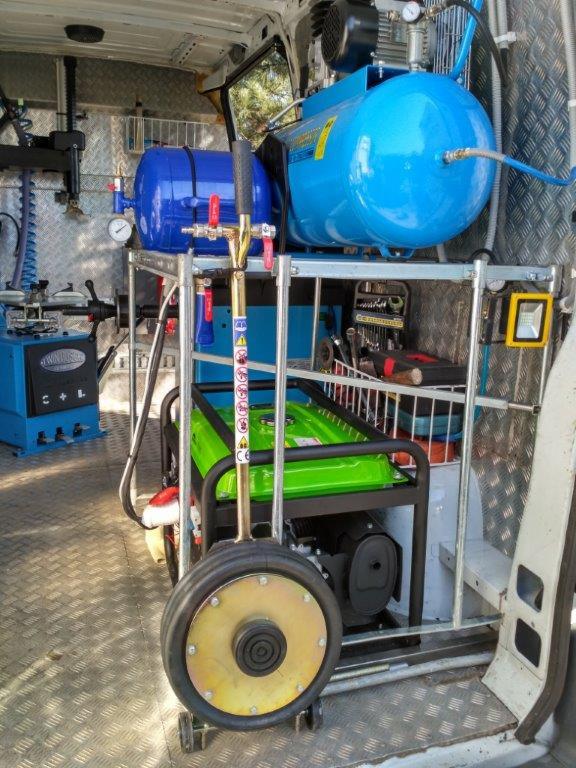 Wnętrze samochodu serwisowego z kompresorami, agregatem prądotwórczym i narzędziami do mobilnego serwisu opon.