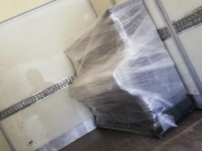 Pianino owinięte folią stretch zabezpieczone wewnątrz furgonetki transportowej z metalowymi szynami mocującymi na ścianach.