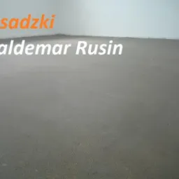 Gładka, szara powierzchnia nowej wylewki podłogowej w jasnym pomieszczeniu, z pomarańczowym napisem 'Posadzki' i białym napisem 'Waldemar Rusin' w lewym górnym rogu.