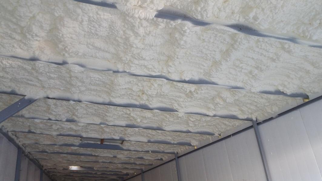 Wnętrze metalowej konstrukcji z natryśniętą, białą izolacją termiczną na suficie, widoczne elementy konstrukcyjne.