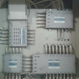 Rozdzielnica elektryczna z zamontowanymi modułami Terra, liczne kable koncentryczne podłączone do wejść i wyjść, widoczne oznaczenia na modułach i listwy zaciskowe.