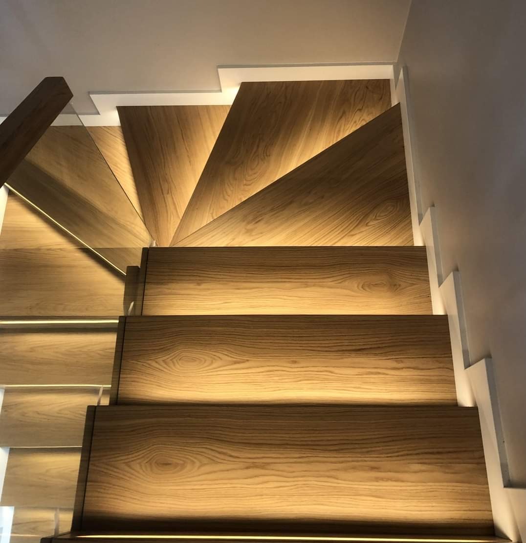 Nowoczesne schody z drewna dębowego z podświetleniem LED pod każdym stopniem, widok z góry ukazuje naturalny rysunek słojów drewna.