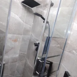 Nowoczesna kabina prysznicowa z czarną armaturą na tle szarych płytek imitujących marmur.