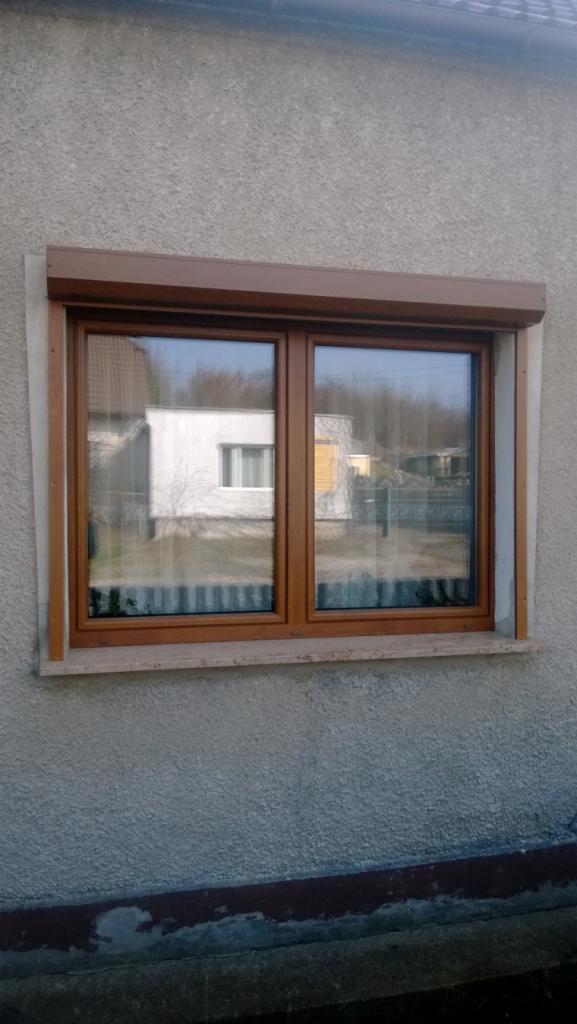 Brązowe okno PCV z roletą zewnętrzną zamontowane w budynku w Szczecinie, widok z zewnątrz.