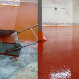 Aplikacja czerwonej, dwuskładnikowej wylewki na betonową posadzkę w pomieszczeniu przemysłowym, z widocznym narzędziem do rozprowadzania i fragmentem gotowej, błyszczącej powierzchni.