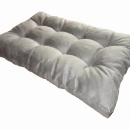 Szara, prostokątna poduszka na krzesło z charakterystycznymi wgłębieniami, leżąca na białym tle, ukazująca miękką teksturę materiału.