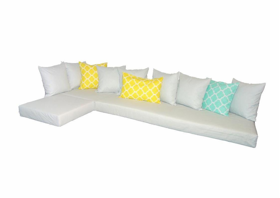 Białe, modułowe siedzisko narożne z kompletem poduszek: białych, żółtych z marokańskim wzorem i turkusową z podobnym motywem.