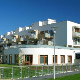 Nowoczesny budynek mieszkalny Marina Mokotów z białymi elewacjami, szklanymi balustradami balkonów i zadbanym terenem zielonym.