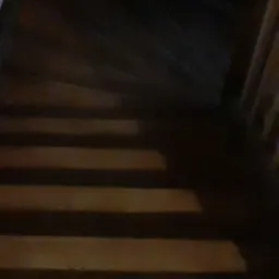 Niedostatecznie oświetlone, drewniane schody widziane z góry, z widoczną balustradą po prawej stronie.