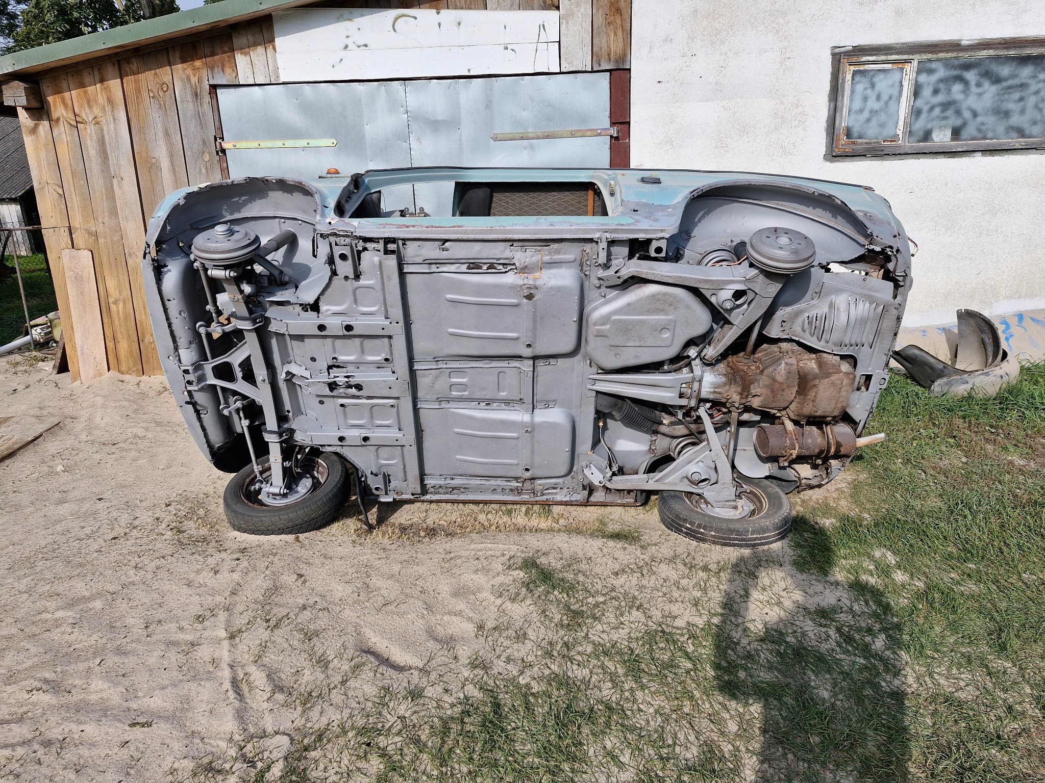 Podwozie samochodu po czyszczeniu i zabezpieczeniu antykorozyjnym, odwrócone do góry kołami na zewnątrz, widoczne detale konstrukcji i zawieszenia.