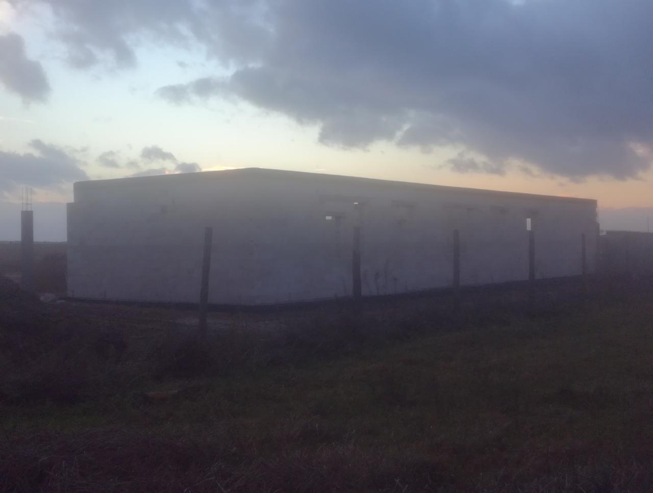 Surowy budynek w trakcie budowy, widoczne ściany z betonu komórkowego w szarym świetle zmierzchu, z wystającymi prętami zbrojeniowymi w tle.