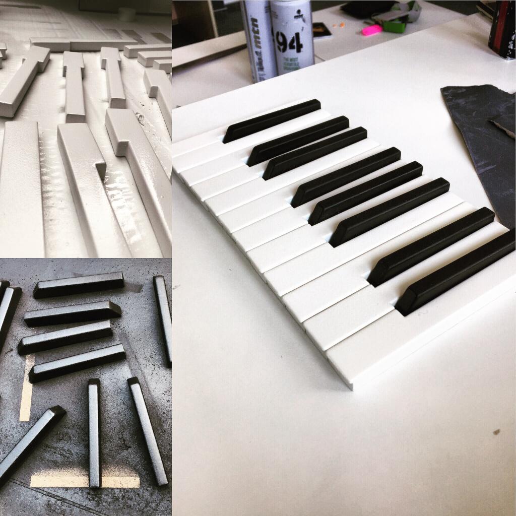 Etapy tworzenia dekoracji ściennej z motywem klawiatury pianina: pomalowane na biało elementy przed montażem, czarne klawisze po malowaniu i gotowy fragment klawiatury na białym tle.
