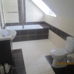 Osoba prywatna - Wykończona łazienka na poddaszu z biało-czarnymi płytkami, umywalką na szafce, toaletą i wanną z parawanem.