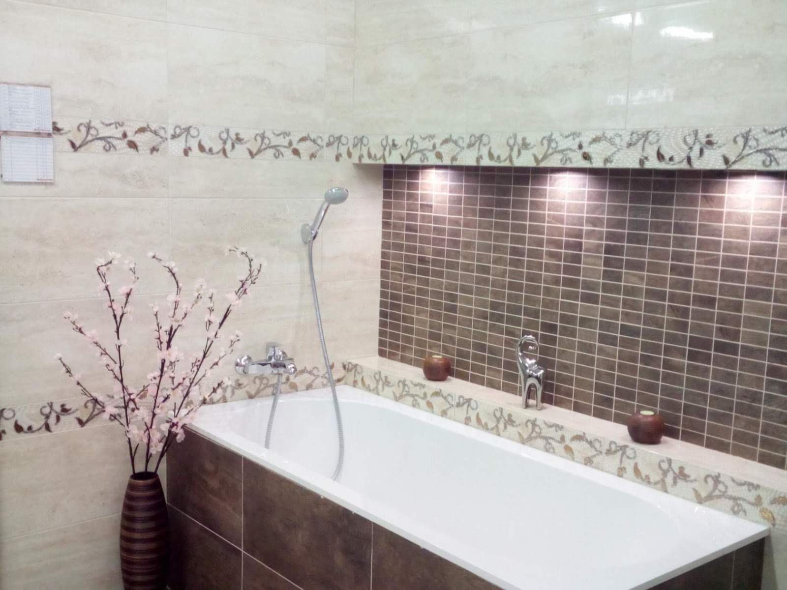 Elegancko wykończona łazienka w Gdańsku z wanną, beżowymi płytkami z dekoracyjnym motywem roślinnym, mozaiką w odcieniach brązu we wnęce oświetlonej punktowo oraz wazonem z kwitnącymi gałązkami.