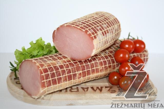 Dwa kawałki wędliny w siatce ułożone na drewnianej desce z pomidorkami cherry i listkami sałaty, z widocznym logo producenta