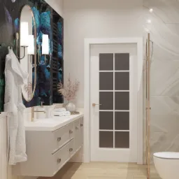 Nowoczesna łazienka z umywalką na szafce w kolorze gołębim, złotą armaturą, dekoracyjną tapetą w kwiaty i kabiną prysznicową ze złotymi okuciami.