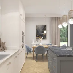 Jasna kuchnia z wyspą i marmurowym blatem, drewnianym stołem z szarymi krzesłami i złotymi lampami wiszącymi, parkiet w jodełkę.