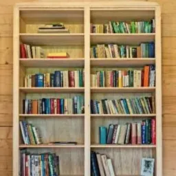 Jasna, drewniana biblioteka na wymiar, wypełniona książkami, z dekoracyjnym szczytem w kształcie trójkąta, na tle drewnianej ściany.