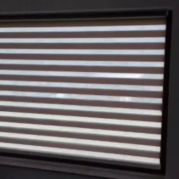 Okno z zamontowaną roletą w biało-brązowe poziome pasy, zapewniającą częściowe zaciemnienie, widok z wnętrza pomieszczenia.