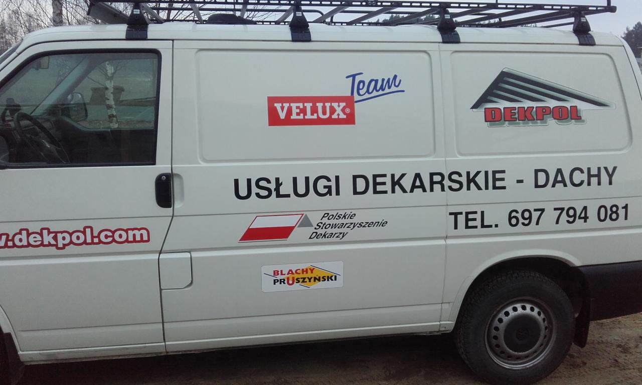 Biały samochód dostawczy z reklamą firmy dekarskiej, widoczne logo Velux, Dekpol, Blachy Pruszyński, numer telefonu i adres strony internetowej.