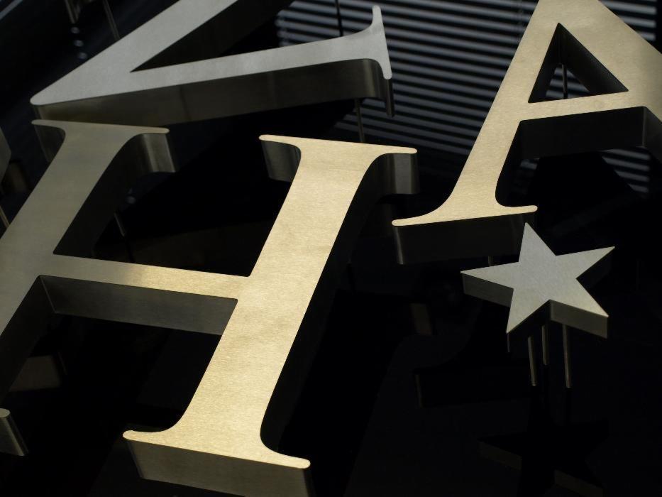 Metalowe litery i gwiazda z efektem 3D, umieszczone na czarnym, błyszczącym tle z subtelnymi refleksami światła.