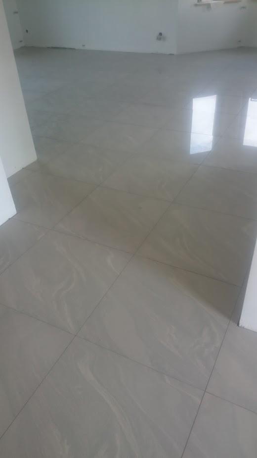 Świeżo położona, błyszcząca, beżowa podłoga z płytek w pustym pokoju. Widoczne odbicie światła na powierzchni płytek.