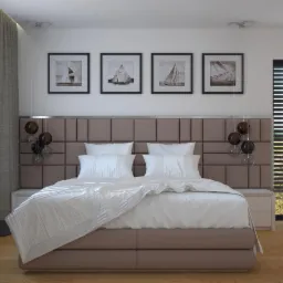Nowoczesna sypialnia z łóżkiem kontynentalnym, panelem tapicerowanym na ścianie, wiszącymi lampami kulami i obrazami z motywem żaglówek.