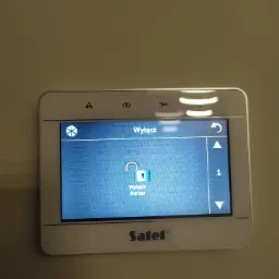 Panel sterowania systemem alarmowym marki Satel z podświetlonym ekranem dotykowym, prezentującym opcję wyłączenia alarmu dla parteru.