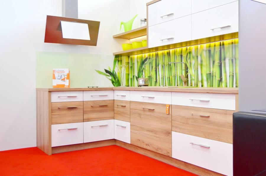 Nowoczesna kuchnia z frontami w kolorze drewna i białym, z blatem z dekorem bambusa i oświetleniem LED, prezentowana na czerwonej wykładzinie.