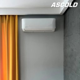 ASCOLD - Biała klimatyzacja Rotenso na szarej ścianie, obok żółta zasłona i betonowa ściana. Widoczny napis Ascold w prawym górnym rogu.