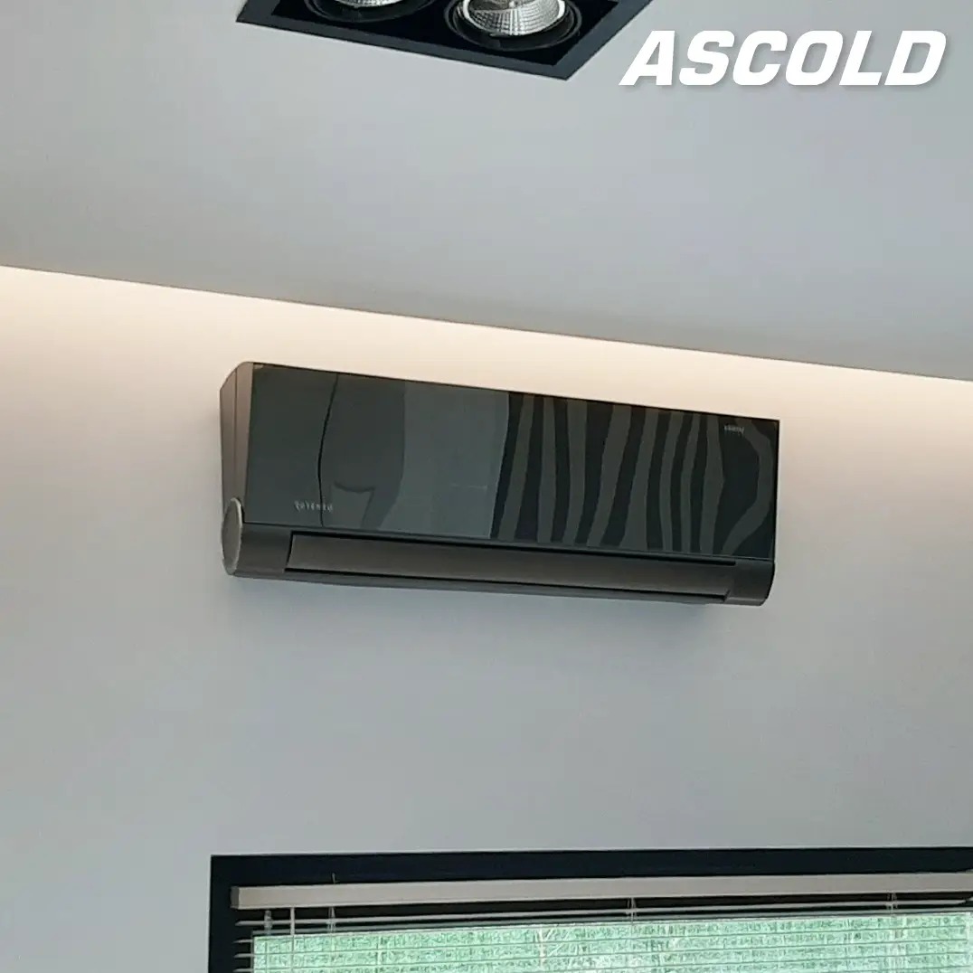 Czarny klimatyzator ścienny z wzorem zebry, zamontowany w nowoczesnym wnętrzu z oświetleniem LED i widocznym fragmentem okna. Logo firmy w prawym górnym rogu.