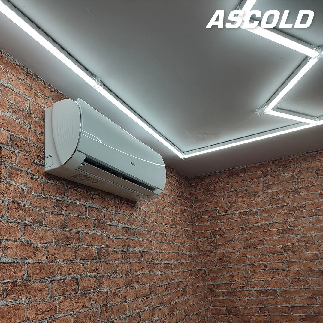 Biały klimatyzator na ceglanej ścianie podświetlony ledami. Widoczne logo producenta. Ujęcie z dołu, podkreślające nowoczesny design i dopasowanie do wnętrza.