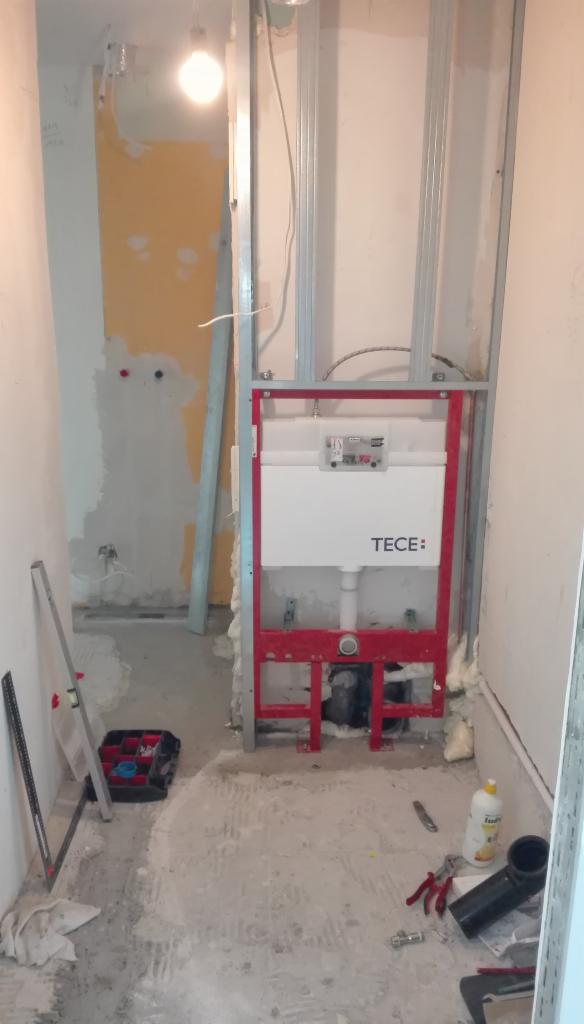 Stelaż podtynkowy TECE zamontowany w łazience w trakcie remontu, widoczne profile metalowe, instalacja wodno-kanalizacyjna oraz narzędzia na podłodze.