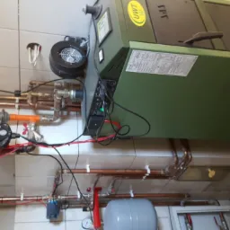 Instalacja kotła grzewczego UWT z miedzianymi rurami i osprzętem na tle białych płytek.