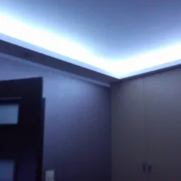 Sufit podwieszany z oświetleniem LED w narożniku pokoju, widok na fragment ściany, drzwi i szafę wbudowaną.