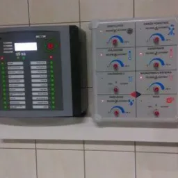 Panel sterowania systemem wentylacji i ogrzewania zamontowany na kafelkowanej ścianie, obok skrzynki elektrycznej w folii ochronnej.