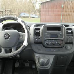 Basik Boerner Wojtasik Sp. J. - Wnętrze Renault Trafic z pokrowcem na kierownicy w biało-czarne paski, widoczna deska rozdzielcza, radio i dźwignia zmiany biegów.