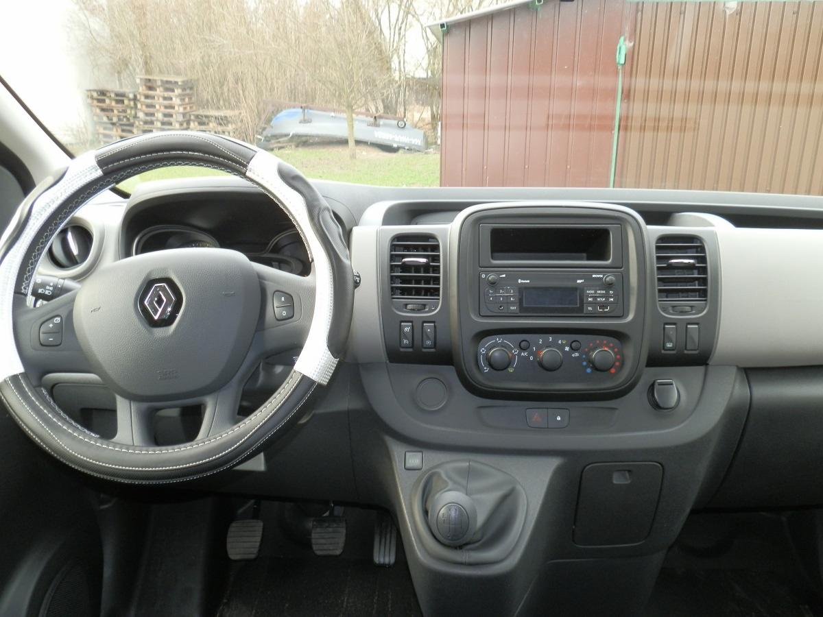 Wnętrze Renault Trafic z pokrowcem na kierownicy w biało-czarne paski, widoczna deska rozdzielcza, radio i dźwignia zmiany biegów.