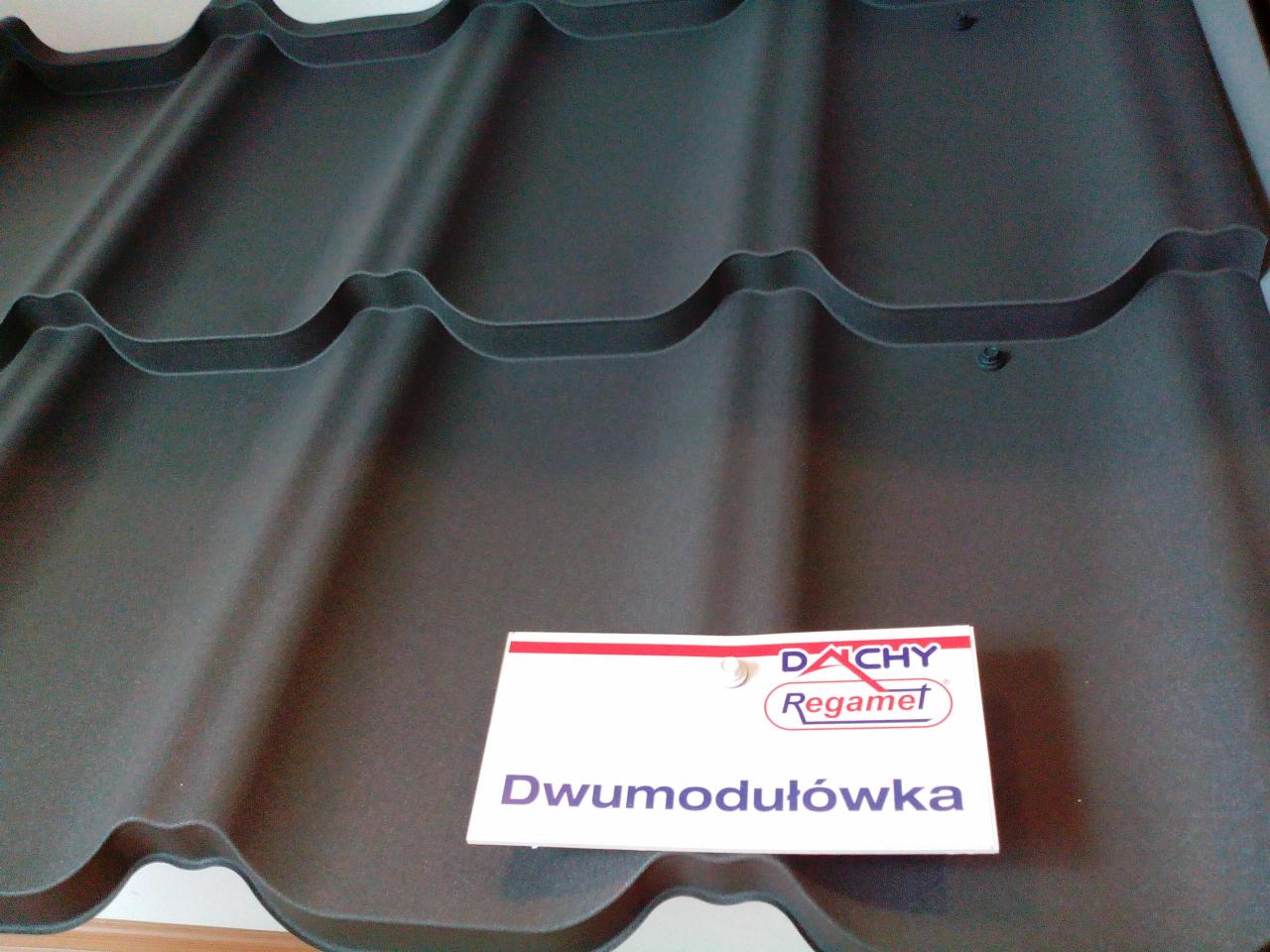 Szare, dwumodułowe dachówki Regamet z widocznym mocowaniem, prezentowane z bliska na ekspozycji.