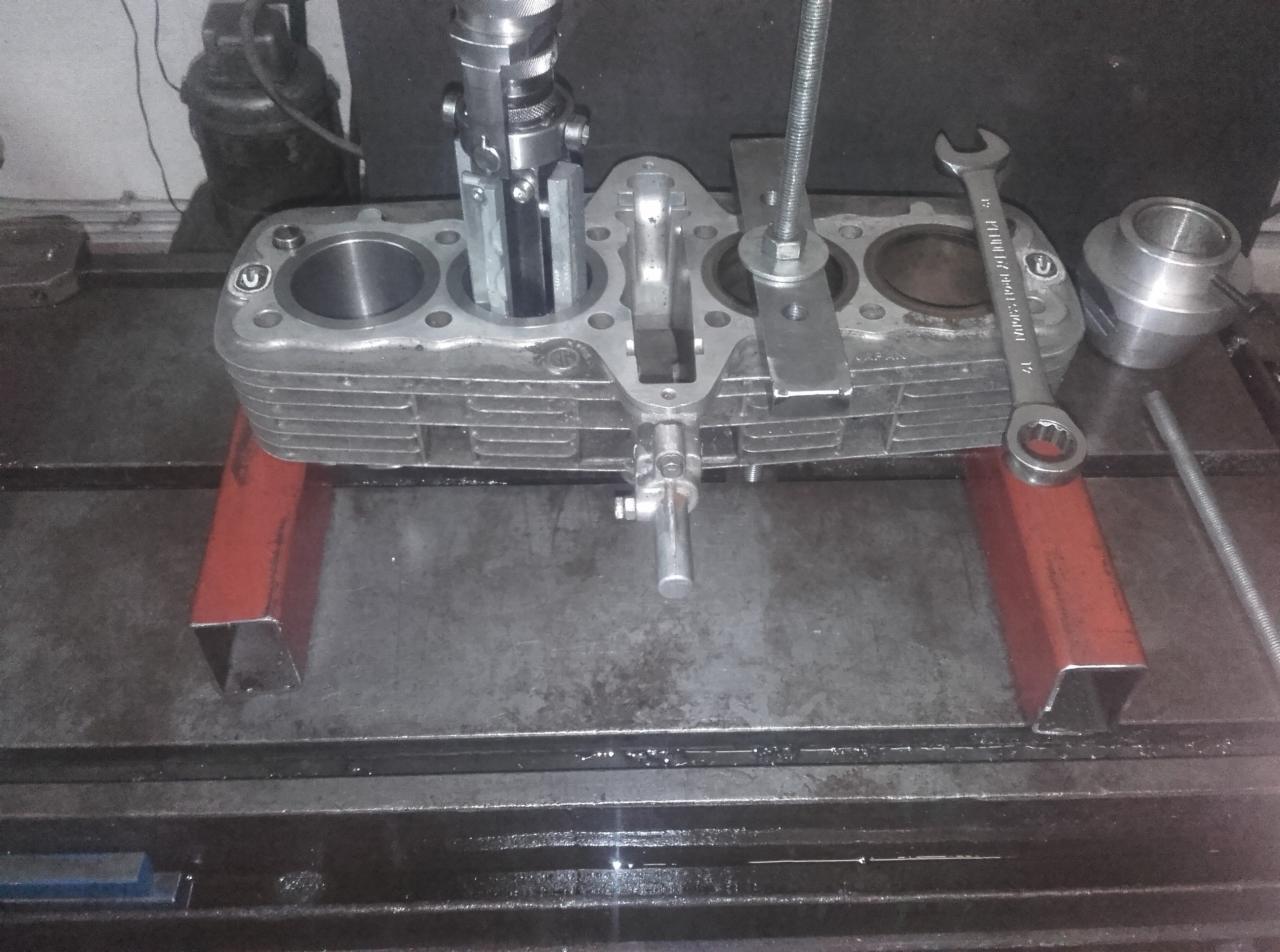 Cylindry silnika motocyklowego na warsztatowym stole, obrabiane narzędziem do honowania, klucz płaski leży obok.